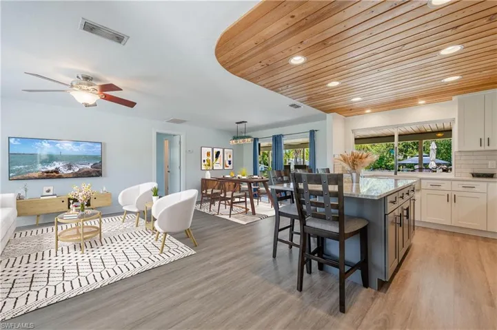 Kitchen featuring backsplash, hanging light fixtures, a breakfast bar area, a center island, and light wood-type flooring