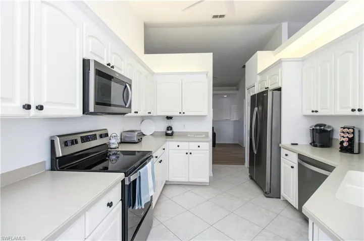 Kitchen featuring white cabinetry, light tile patterned floors, and appliances with stainless steel finishes