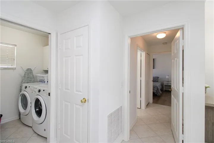 Washroom with independent washer and dryer and light tile patterned flooring
