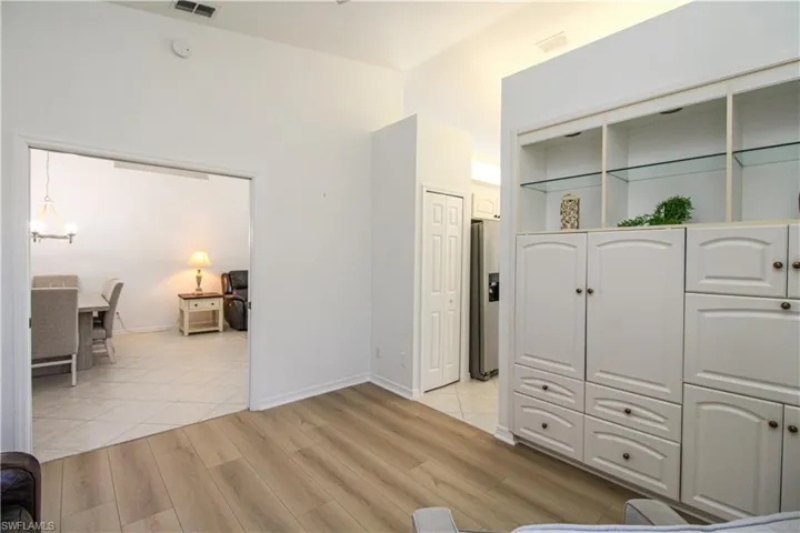 Bedroom featuring stainless steel refrigerator with ice dispenser, light wood-type flooring, and a notable chandelier