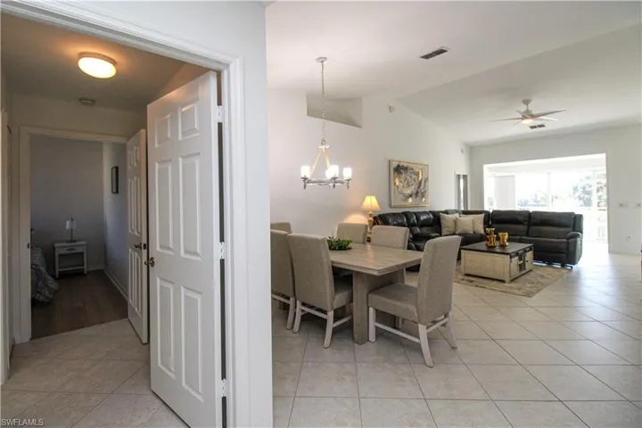 Dining area featuring ceiling fan with notable chandelier, light tile patterned floors, and lofted ceiling