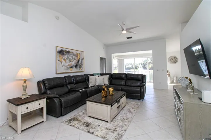 Tiled living room with ceiling fan and lofted ceiling
