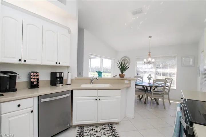 Kitchen with white cabinets, dishwasher, sink, and decorative light fixtures