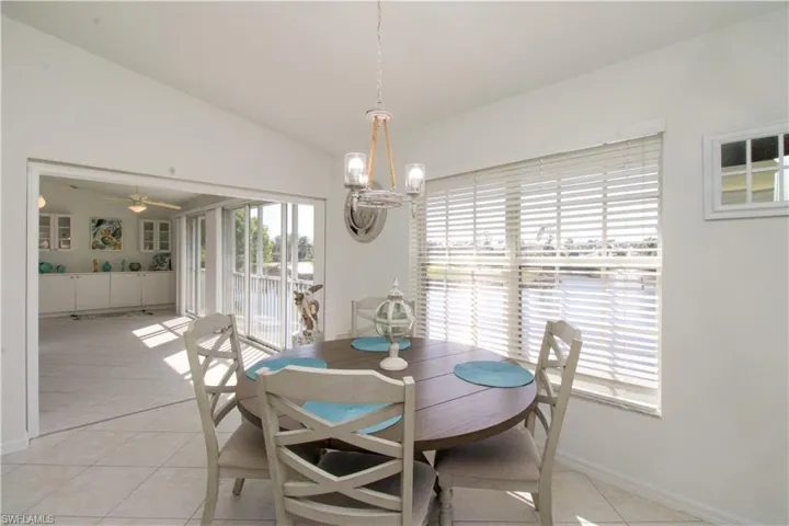 Dining space with ceiling fan with notable chandelier, light tile patterned flooring, and lofted ceiling