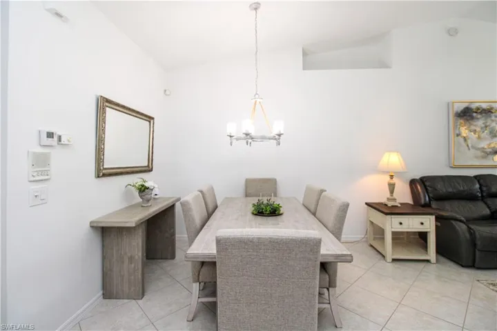 Tiled dining room with an inviting chandelier and vaulted ceiling