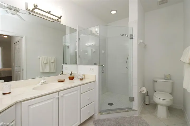 Bathroom featuring tile patterned floors, toilet, vanity, and walk in shower
