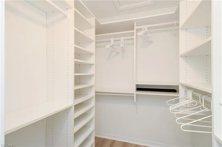 Walk in closet with light hardwood / wood-style floors