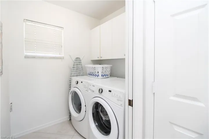 Laundry area featuring light tile patterned floors, cabinets, and independent washer and dryer
