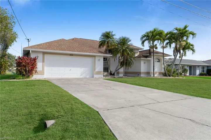 Ranch-style house featuring an attached garage, stucco siding, concrete driveway, and a front yard