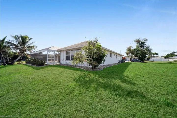 Rear view of property featuring a sunroom, a lanai, and a lawn