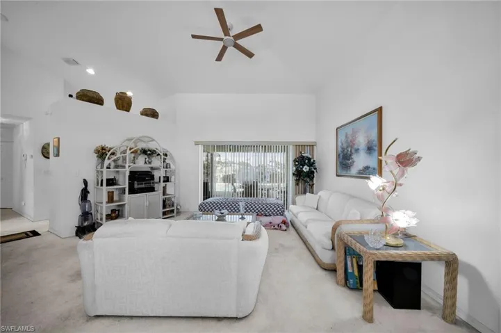 Living area featuring carpet flooring, a ceiling fan, and a high ceiling