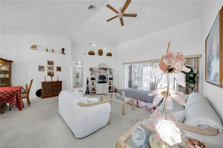 Living area featuring ceiling fan, carpet, and lofted ceiling