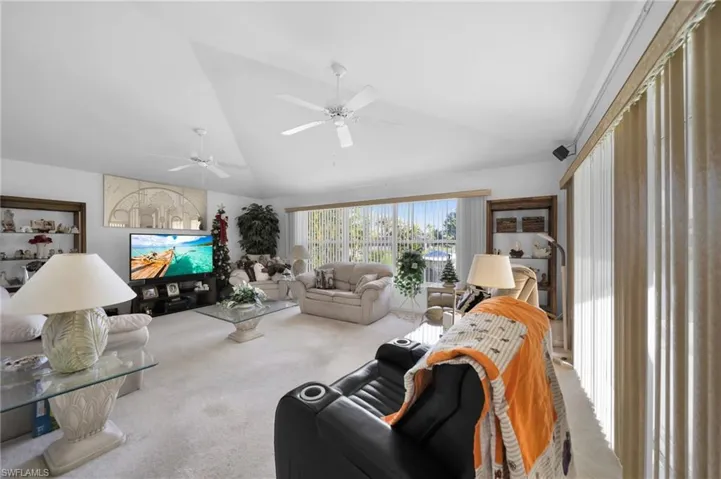 Living area with carpet floors, lofted ceiling, and ceiling fan