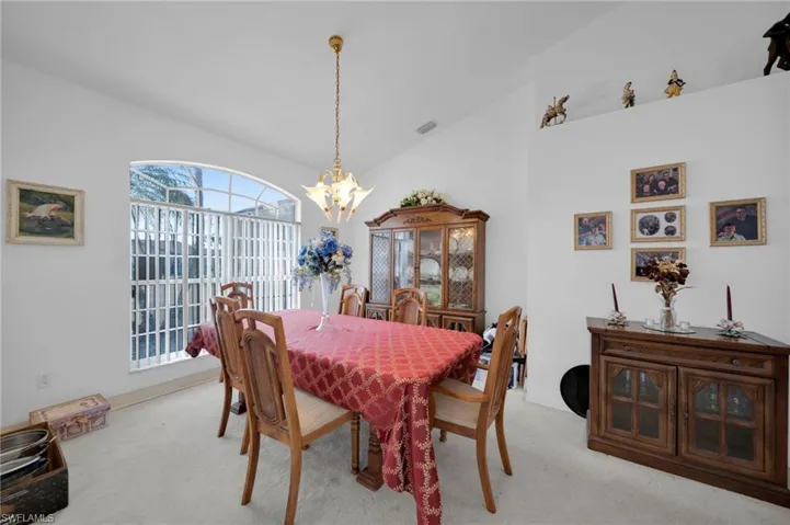 Dining room with lofted ceiling, carpet floors, and hanging lights