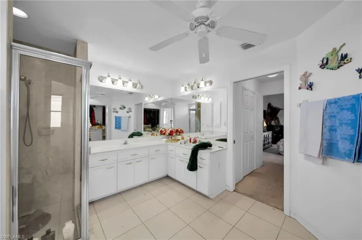 Bathroom with vanity, ceiling fan, a shower stall, and light tile patterned flooring