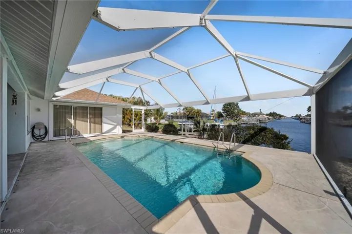 Outdoor pool with a sunroom, a patio area, and glass enclosure