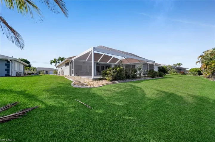 Rear view of property featuring a lanai, a sunroom, and a yard