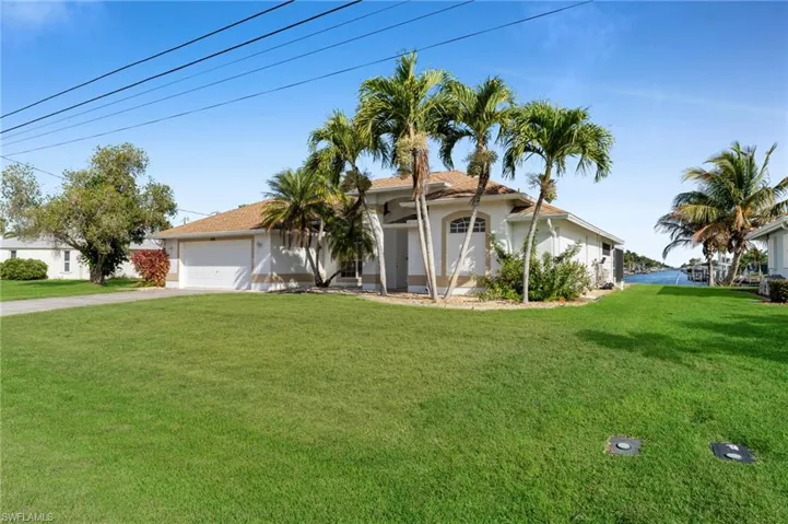 View of front facade with a front yard, driveway, an attached garage, and stucco siding