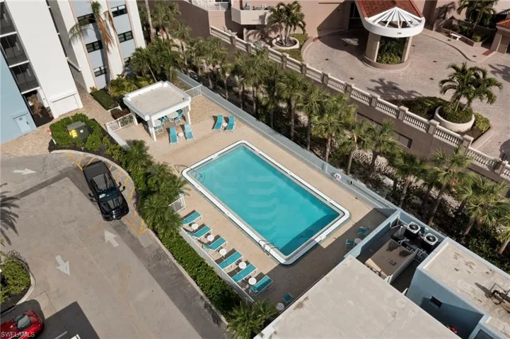 Aerial view of the pool and cabana featuring a grill, tables, chairs, lounges.  Pool bathroom and shower at other end.