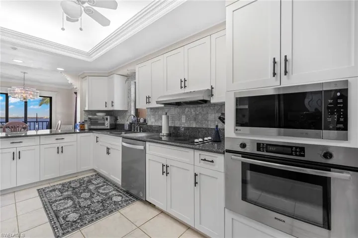 Updated kitchen with white shaker cabinets, black hardware, gray/blue granite & stainless steel appliances.