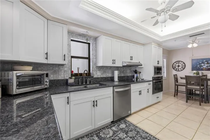 Updated kitchen with white shaker cabinets, black hardware, gray/blue granite & stainless steel appliances.