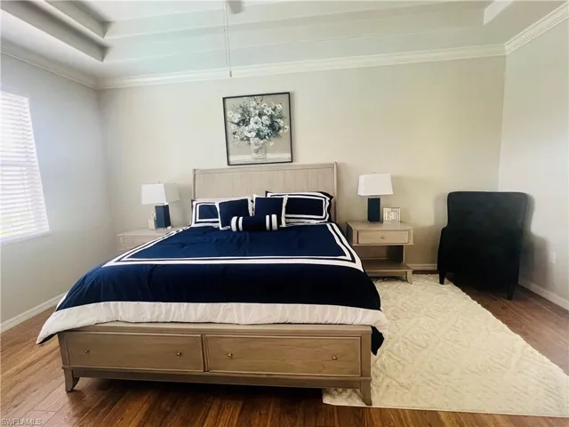 Bedroom featuring ornamental molding, a raised ceiling, and hardwood / wood-style floors
