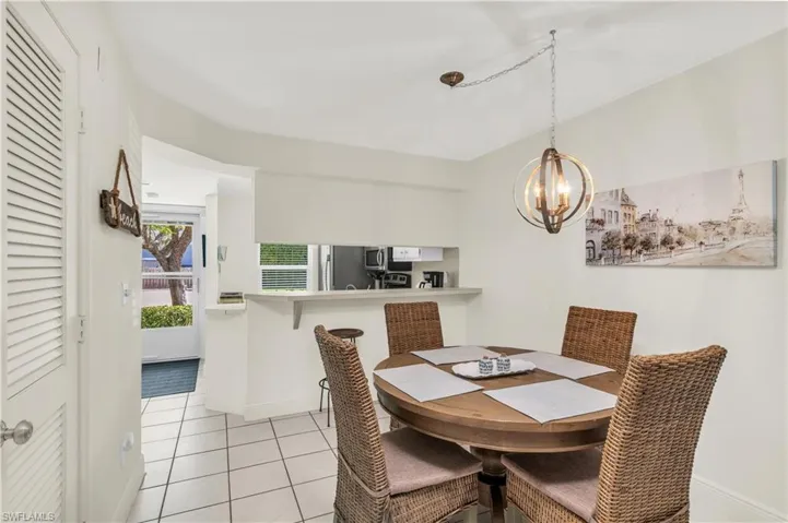Dining room featuring light tile patterned flooring, baseboards, and an inviting chandelier