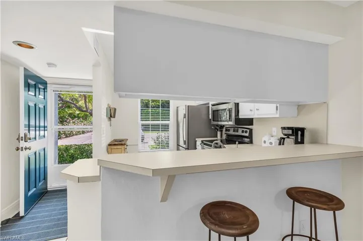 Kitchen featuring light countertops, a breakfast bar area, white cabinets,appliances with stainless steel finishes