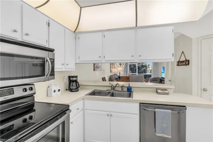 Kitchen featuring light countertops, breakfast bar, stainless steel appliances, white cabinetry, and a sink