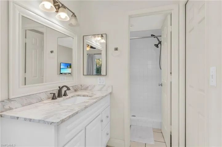 Full bath with tile patterned floors, a tile shower, and vanity, walk in closet.