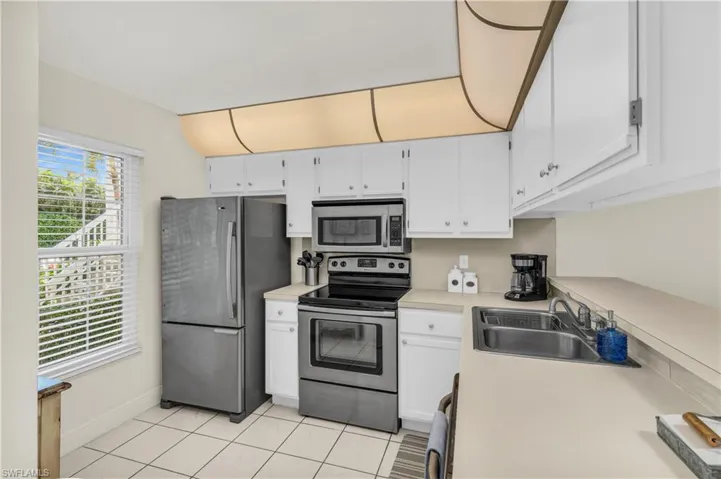 Kitchen with white cabinetry, light countertops, a sink, and appliances with stainless steel finishes