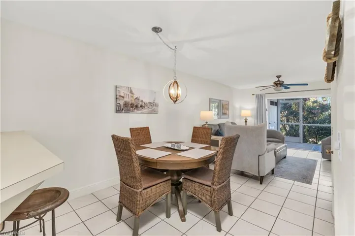 Dining room with ceiling fan with notable chandelier, baseboards, and light tile patterned floors