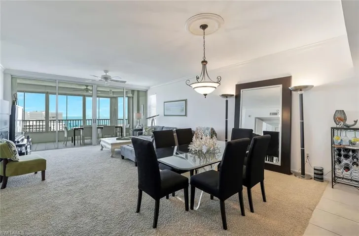 Dining space with crown molding, light colored carpet, ceiling fan, and expansive windows
