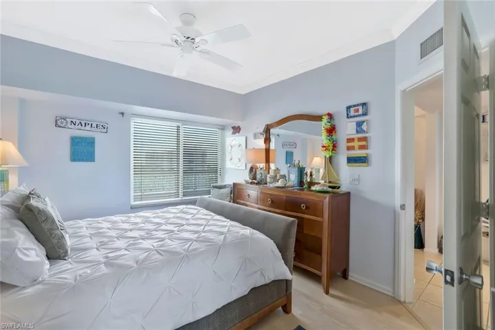 Bedroom with crown molding, light wood finished floors, and a ceiling fan