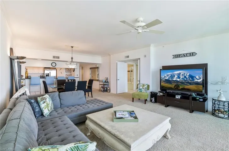 Living room featuring light carpet, ornamental molding, and ceiling fan