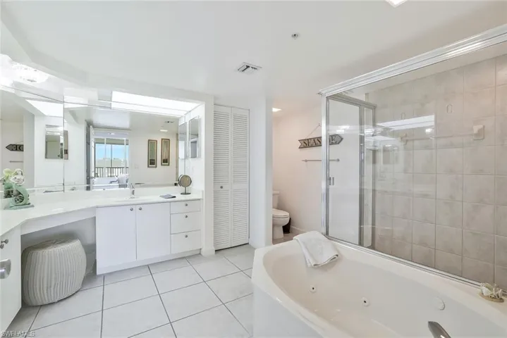 Full bathroom with a closet, a tub with jets, an enclosed shower, vanity, and tile patterned floors