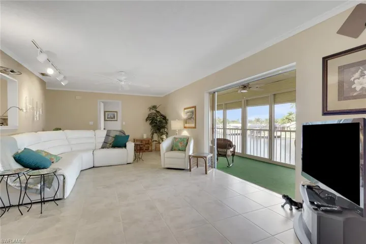 Living room featuring crown molding, rail lighting, light tile patterned flooring, and a ceiling fan
