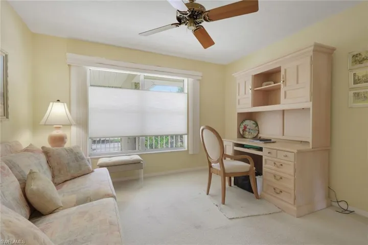 Carpeted office space featuring a ceiling fan and baseboards
