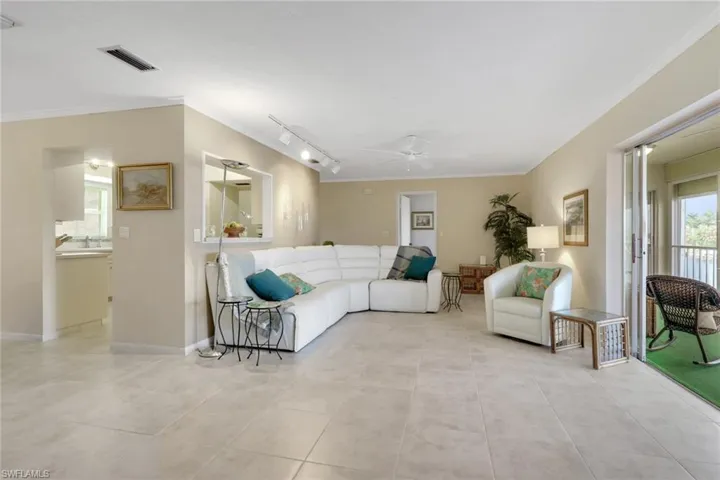 Living room with healthy amount of natural light, crown molding, rail lighting, and a ceiling fan