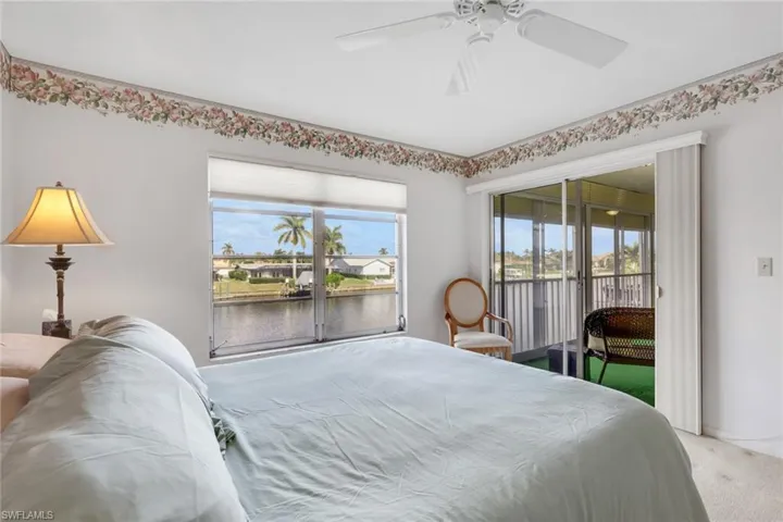 Carpeted bedroom featuring a water view, access to exterior, and a ceiling fan