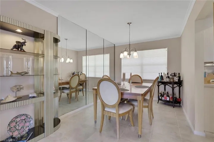 Tiled dining area with crown molding and a chandelier