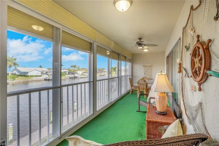 Sunroom with a water view, carpet floors, ceiling fan, and a residential view