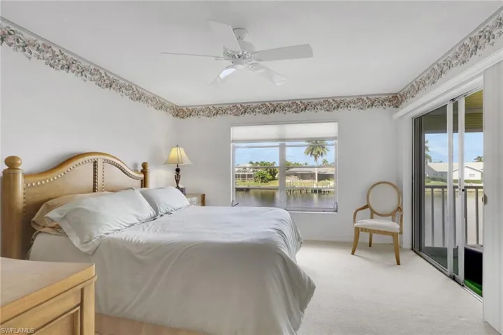 Carpeted bedroom with access to exterior, a water view, and a ceiling fan