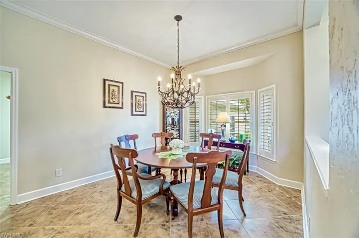 Dining space with ornamental molding and an inviting chandelier
