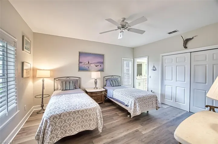 Third guest bedroom featuring hardwood / wood-style flooring, ceiling fan, multiple windows, and a closet