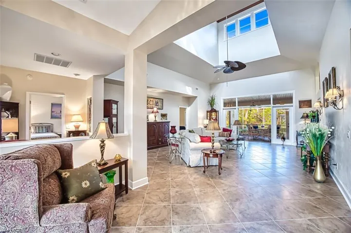 Living room with ceiling fan, light tile patterned floors, and high vaulted ceiling