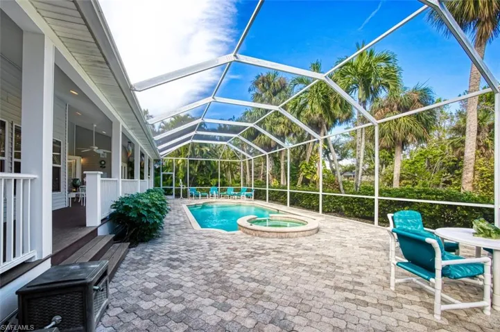 View of pool featuring a patio, glass enclosure, ceiling fan, and an in ground hot tub