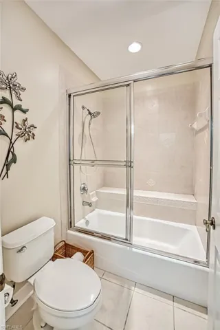 Bathroom featuring shower / bath combination with glass door, tile patterned floors, and toilet