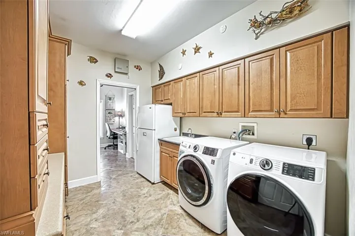 Washroom with cabinets, sink, and washing machine and clothes dryer