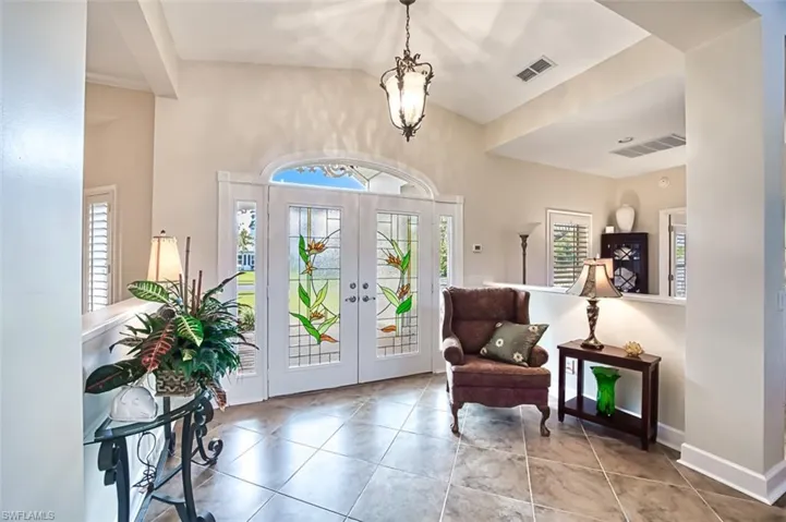 Tiled entrance foyer with french doors and a chandelier